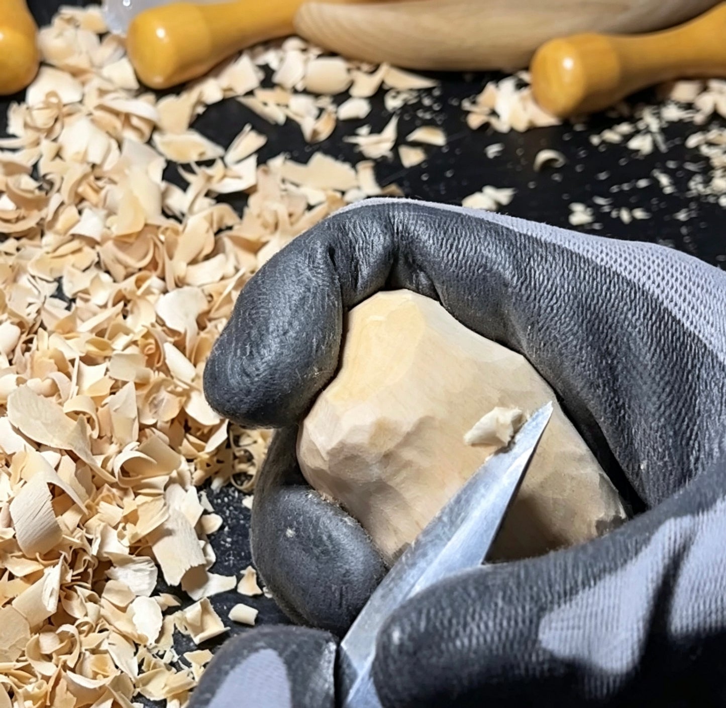 An artisan hand-carving the details of a wooden cloud ornament, surrounded by wood shavings, showcasing the authentic handmade craftsmanship