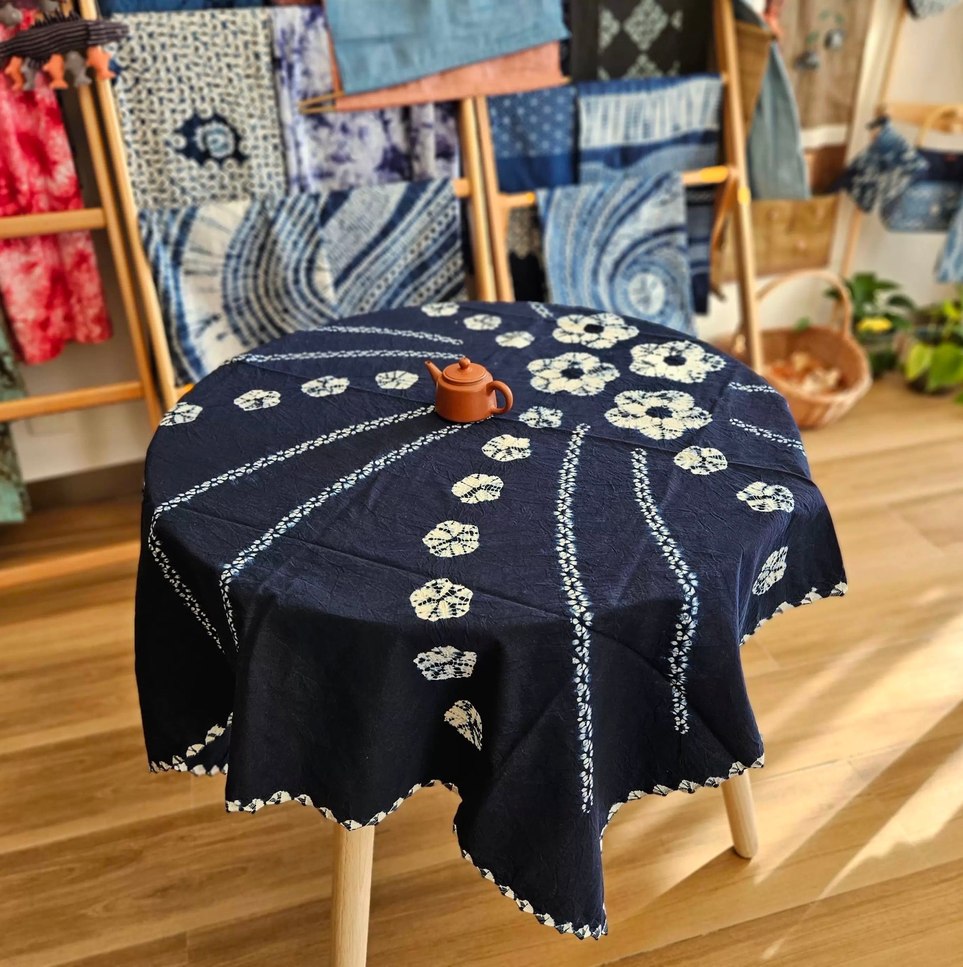 A 43-inch indigo blue tie-dye tablecloth on a round wooden table, traditional botanical dye decor for a soulful dining or tea space.