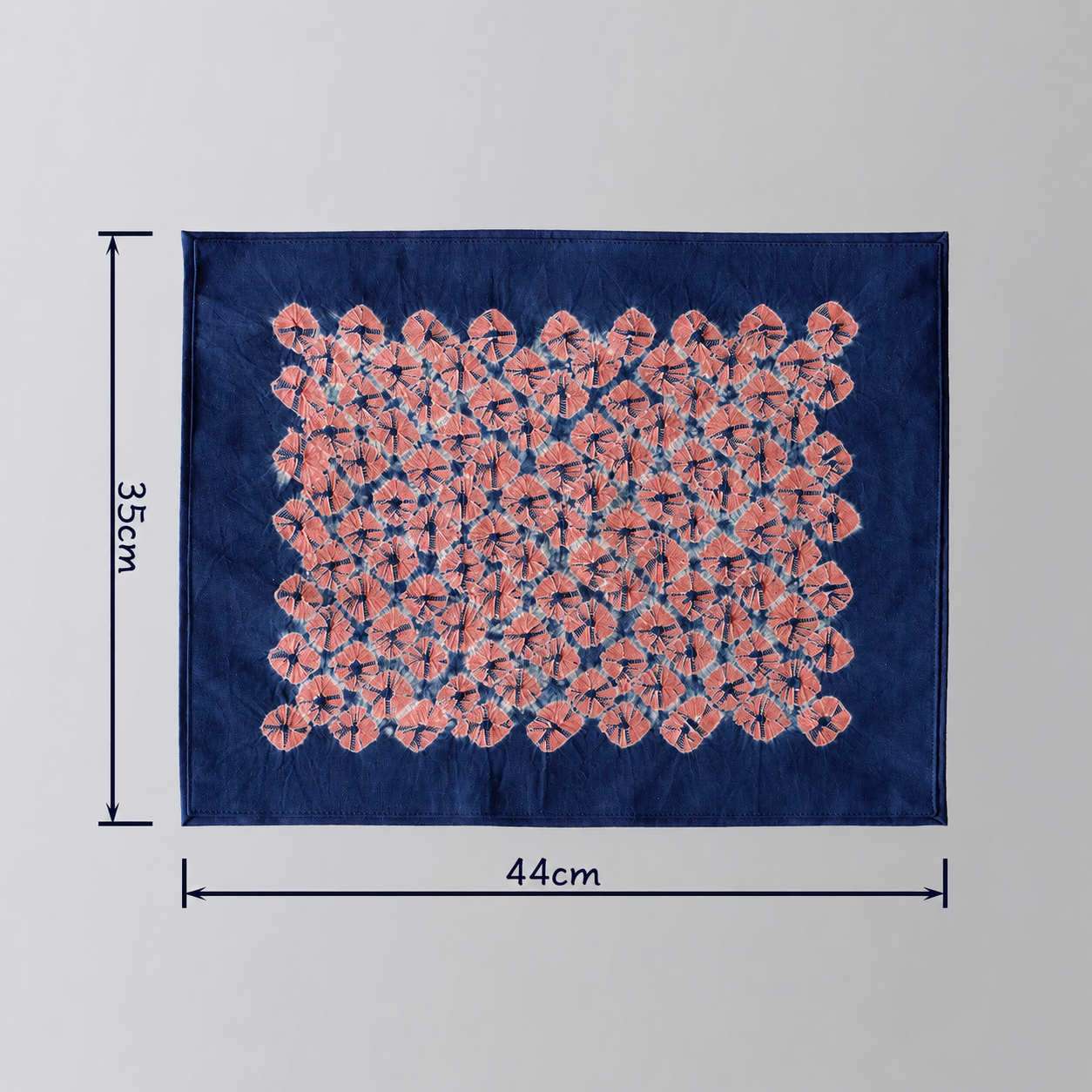 44x35cm hand-dyed cotton mat with a distinct pink geometric pattern on deep indigo blue fabric, traditional Yunnan tie-dye.