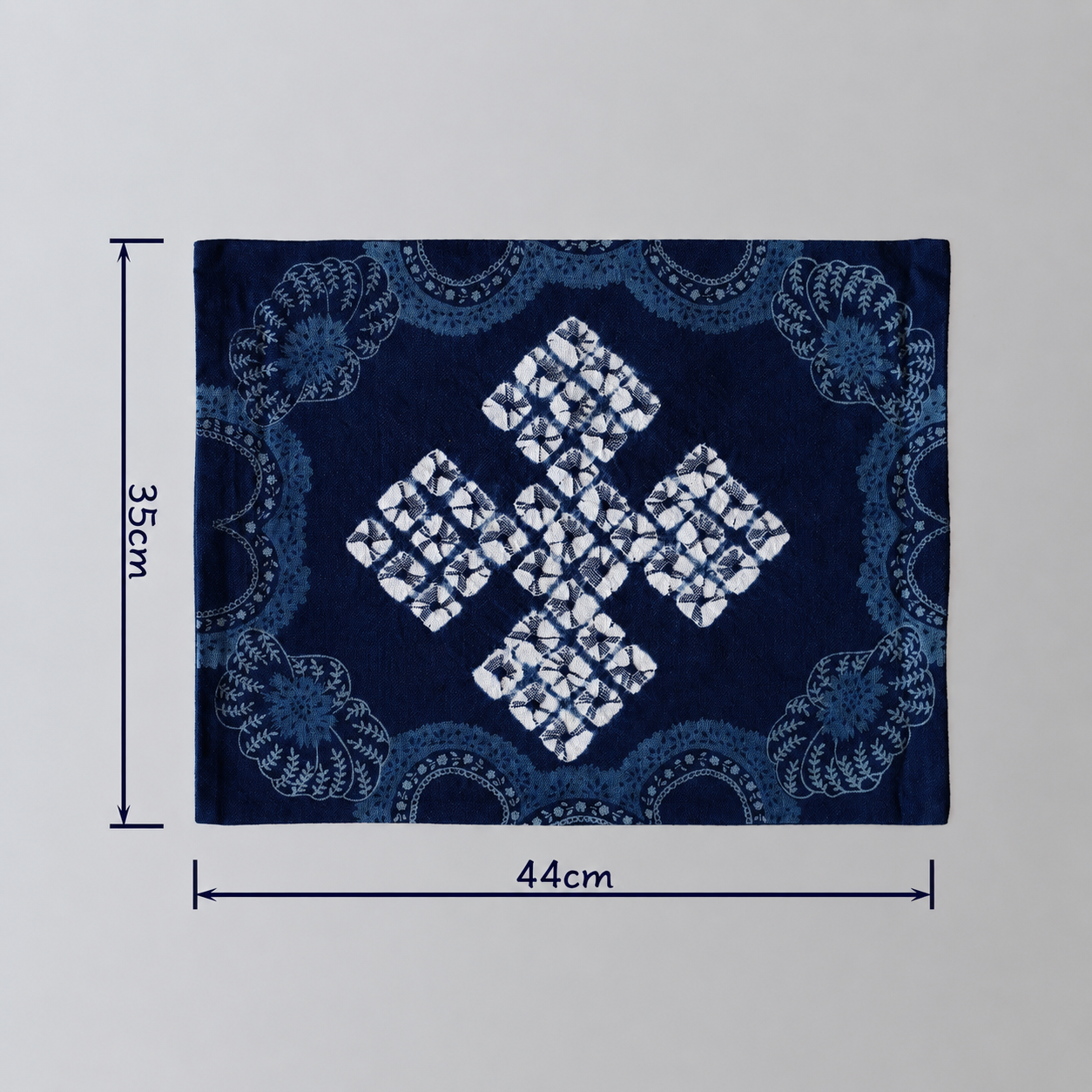 44x35cm artisanal indigo blue cotton mat featuring a traditional symmetrical geometric and floral tie-dye pattern, handcrafted from Yunnan.