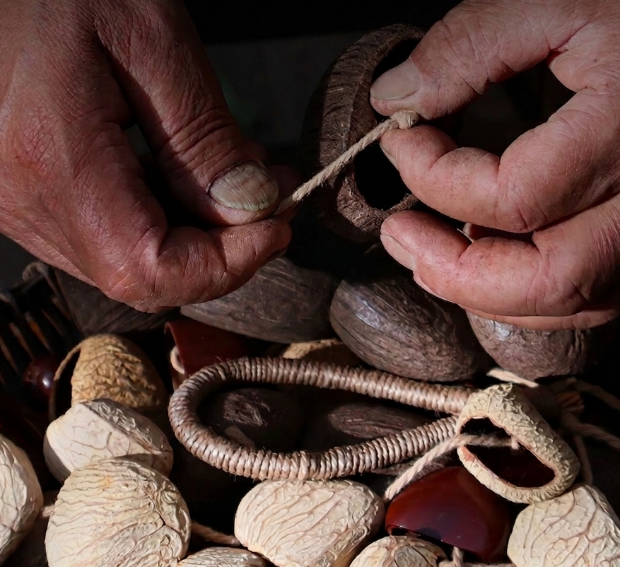 Detailed view of artisan hands hand-weaving Panji shells with natural hemp rope, demonstrating the authentic craftsmanship of traditional ethnic instruments.