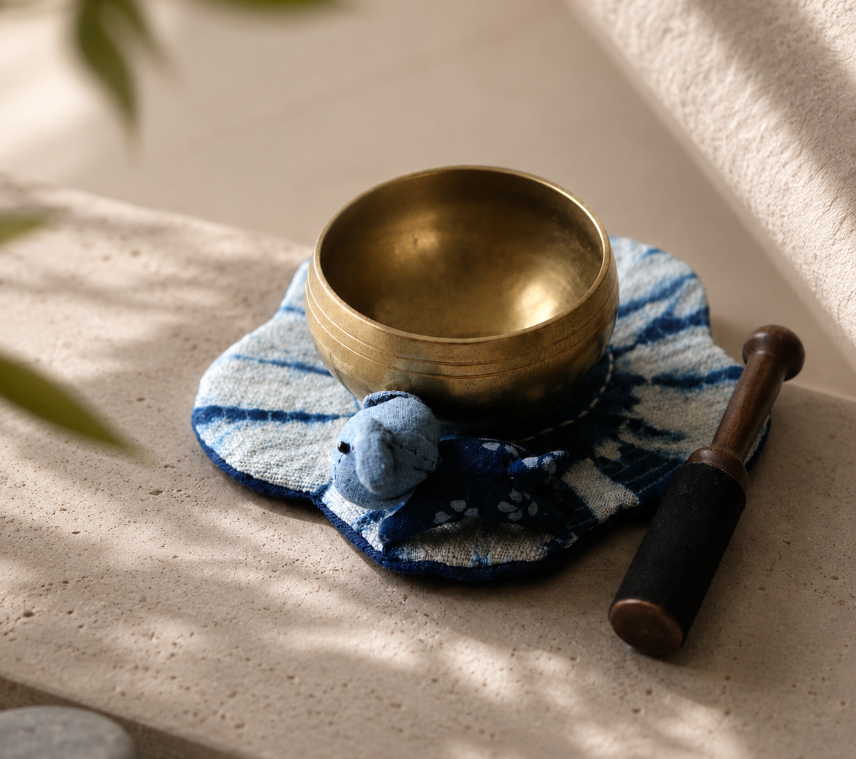 Handmade indigo fabric coaster with brass singing bowl and wooden mallet in a calming healing space