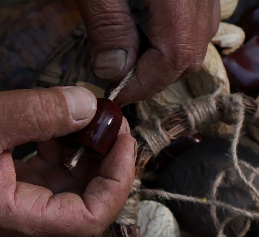 Close-up of artisan hands crafting a Pala natural fruit shell percussion shaker with sustainable materials
