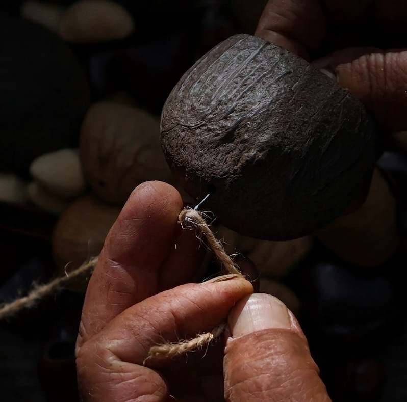 Artisanal crafting detail: stringing natural Salin shells to create a decorative hanging.